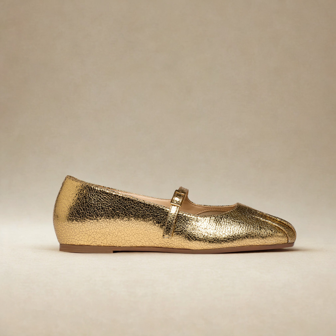 Gold metallic flat shoe on a beige background