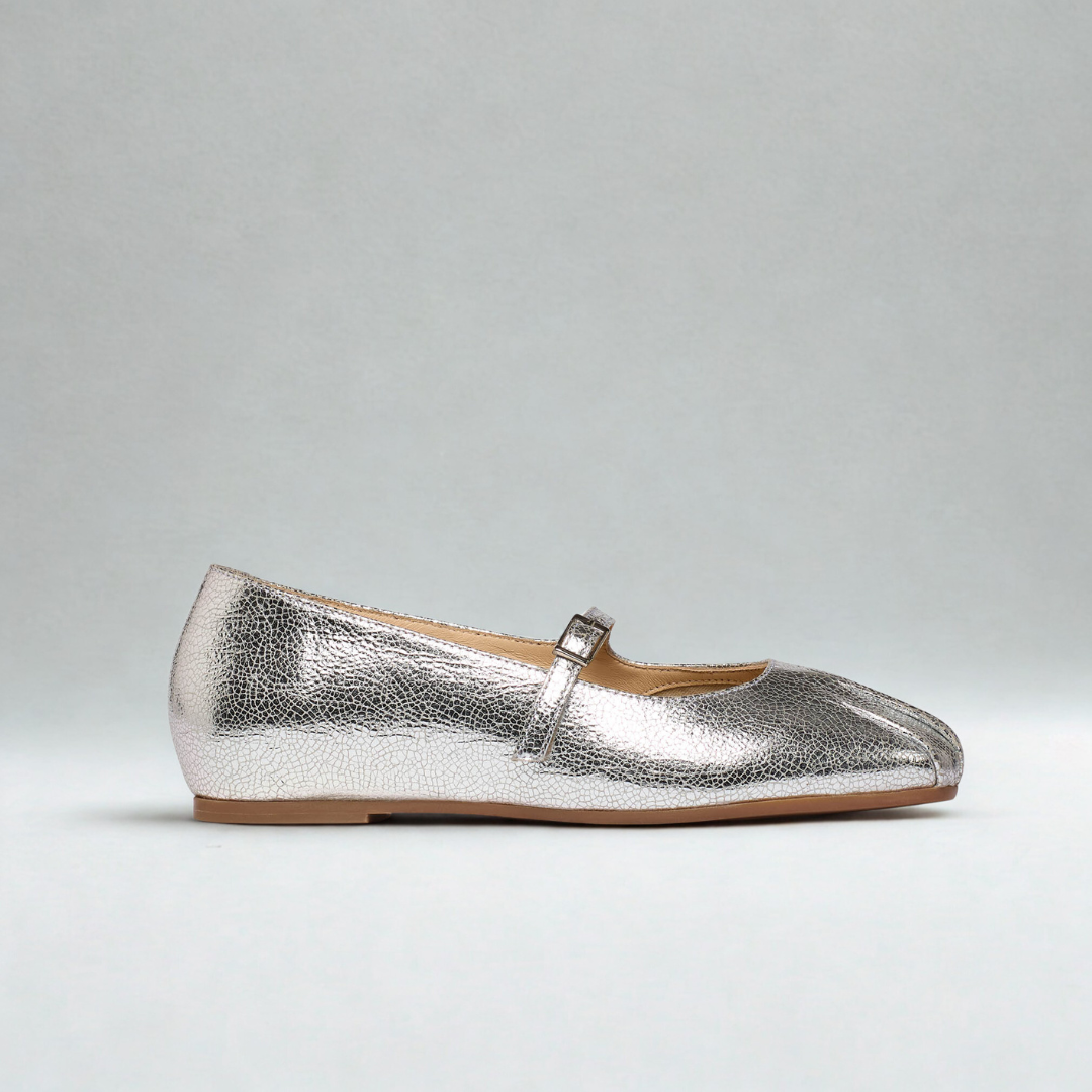 Silver metallic flat shoe with a strap on a gray background