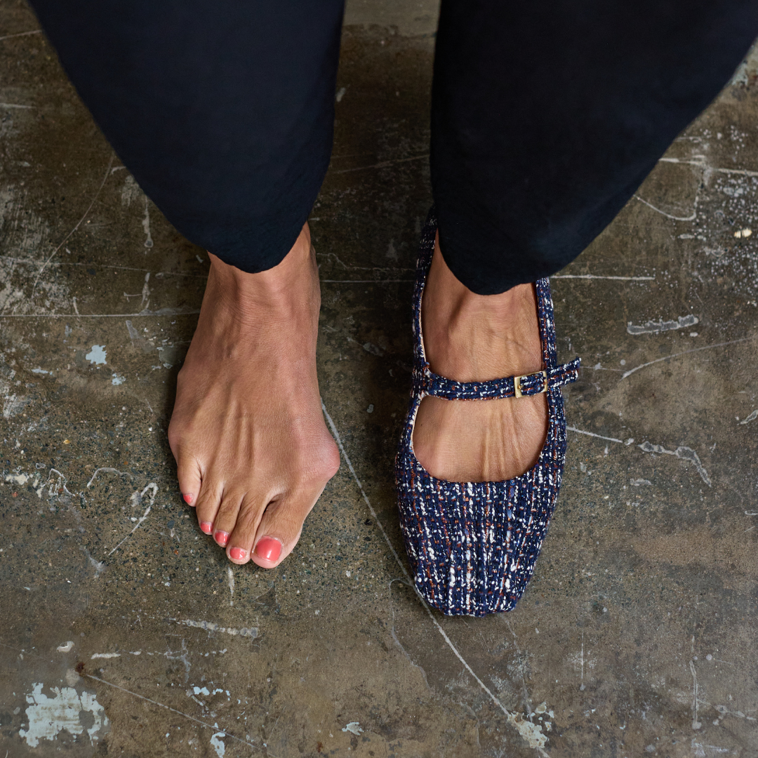 Person wearing a blue tweed flat shoe on a concrete floor