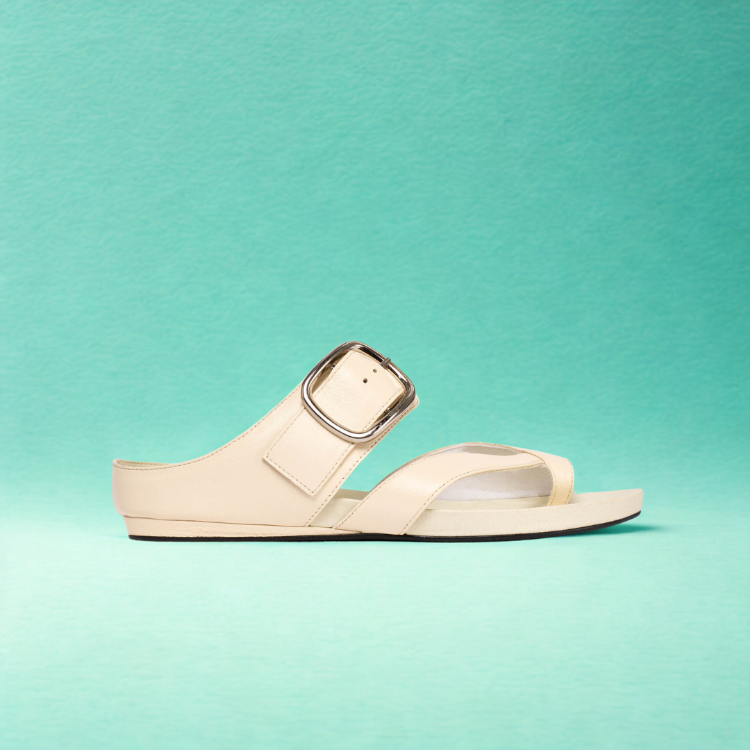 Beige sandal with a clear strap on a teal background