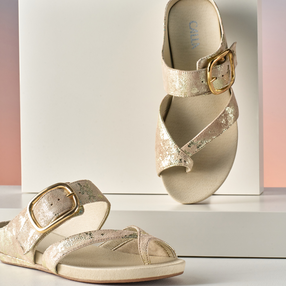 Pair of gold sandals with buckles on a white surface
