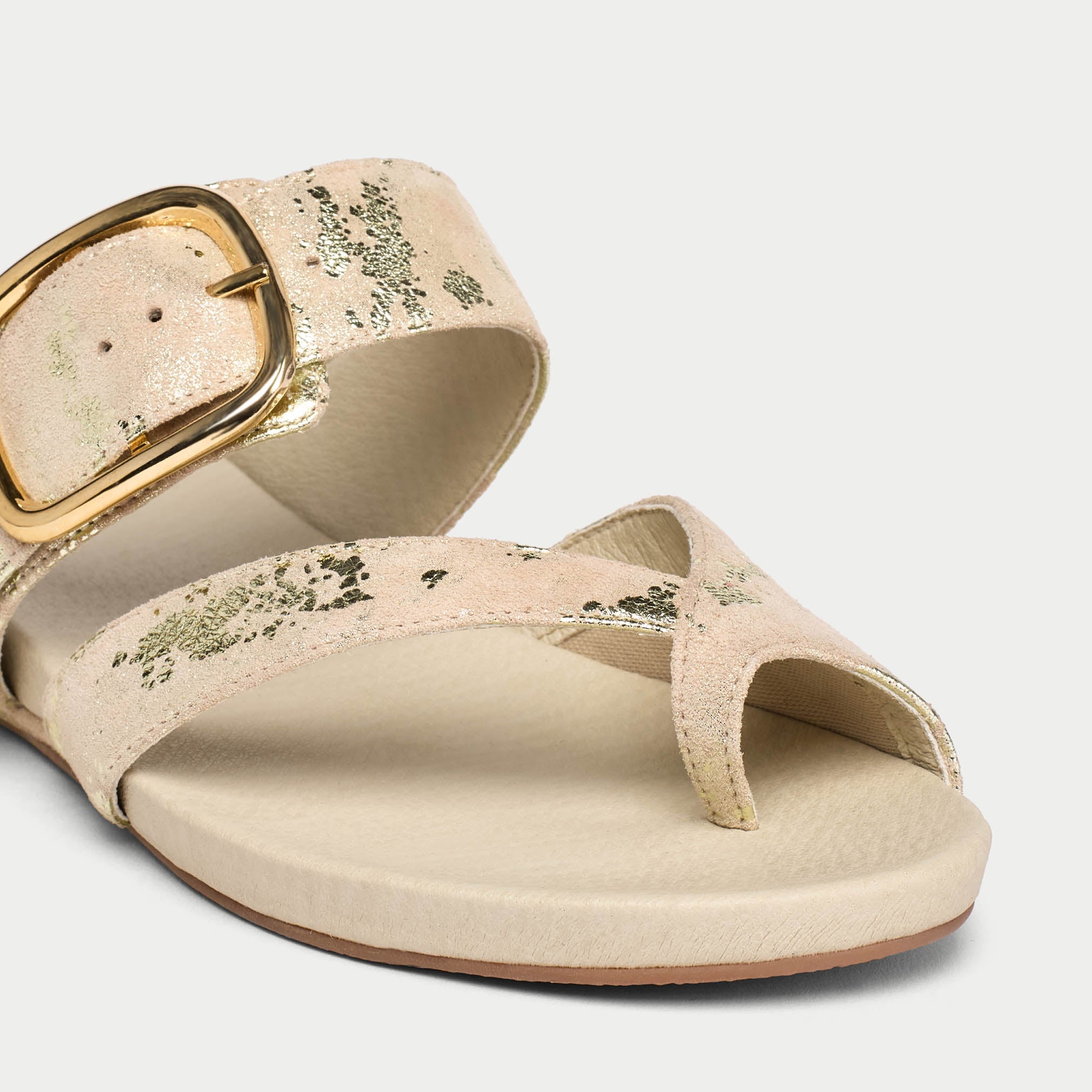 Beige sandal with gold buckle on a light gray background