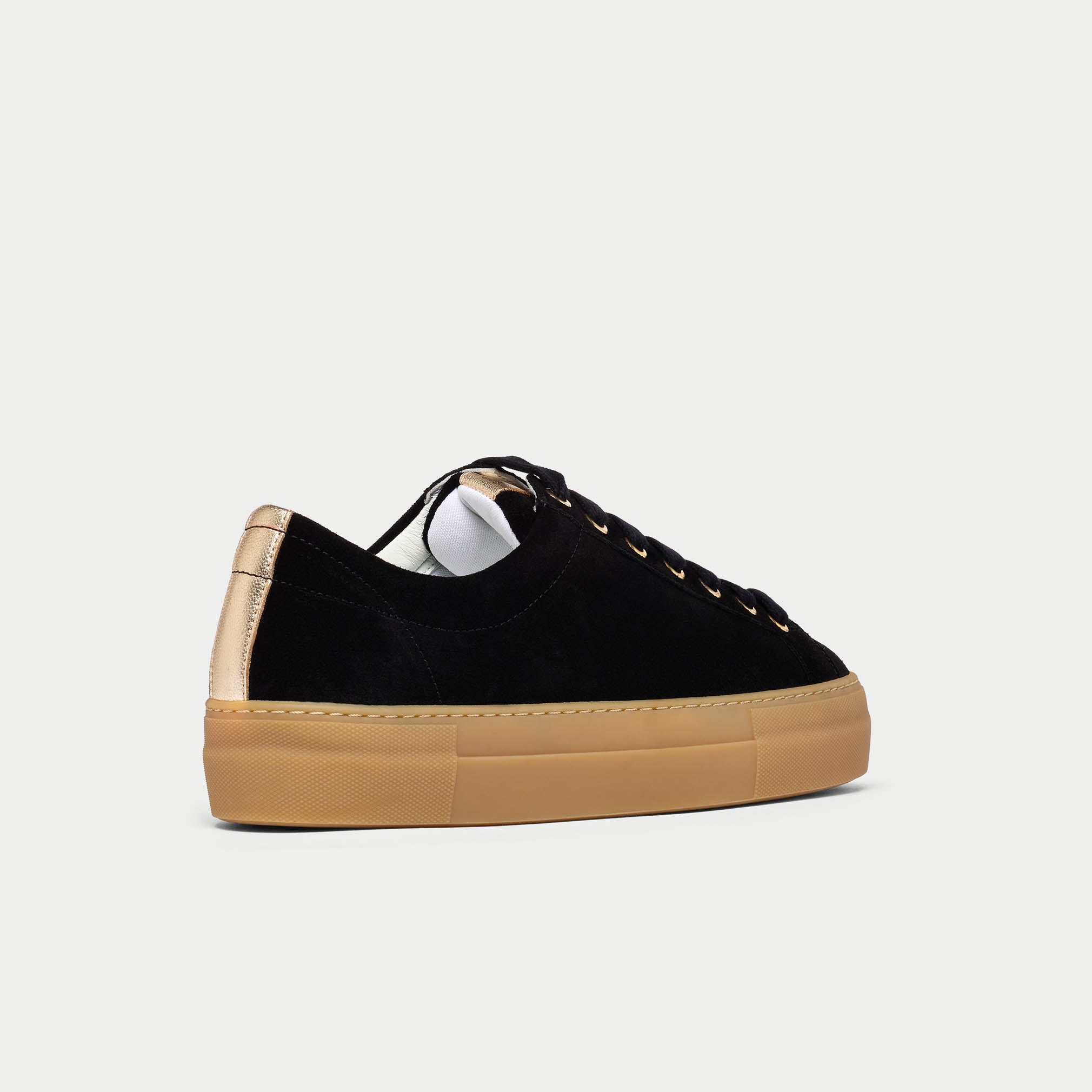 Black Saturn sneakers with tan soles and gold accents on a light gray background side view