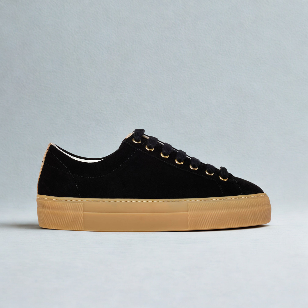 Black sneaker with tan sole on a light gray background