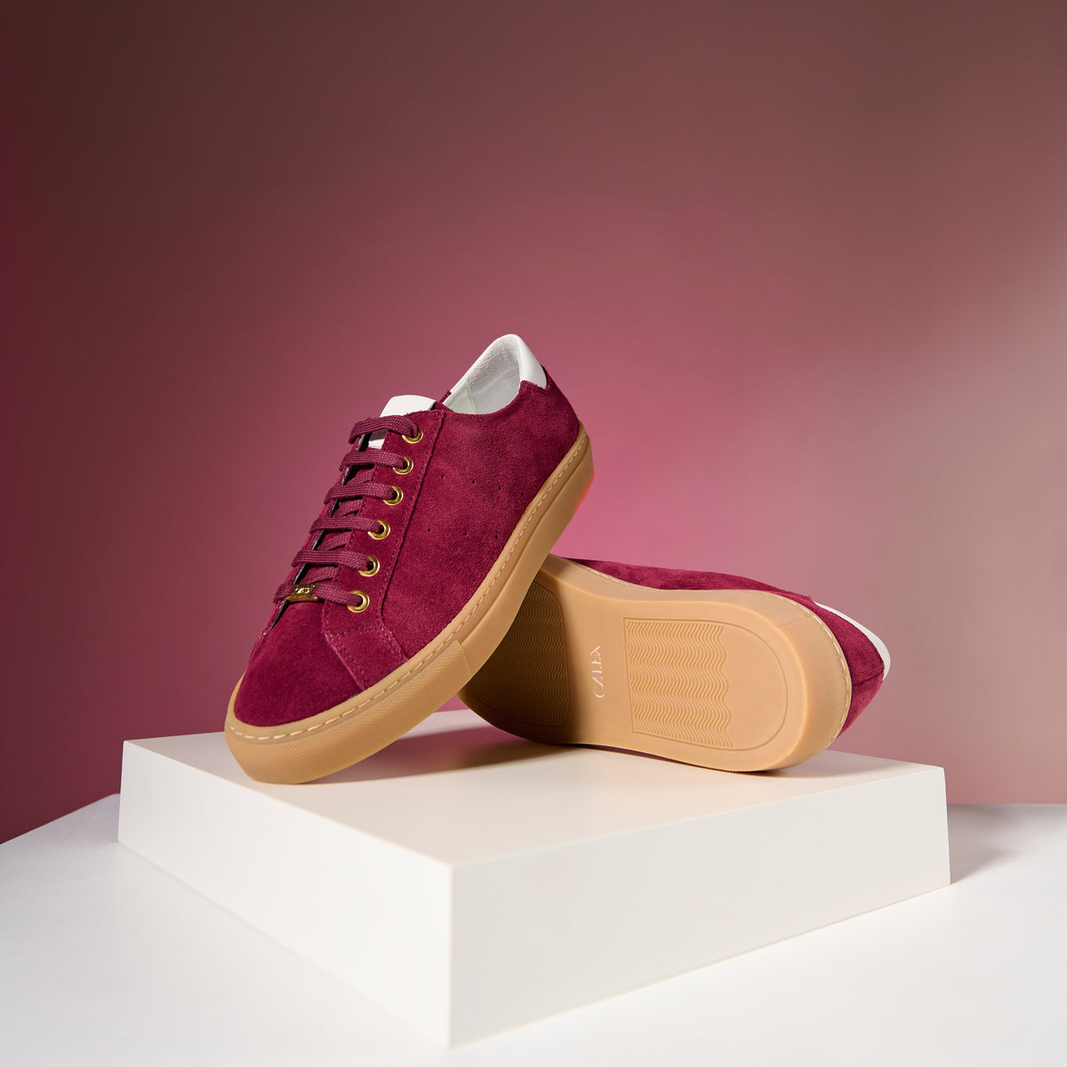 star cherry sneakers with tan soles on a white platform against a pink background