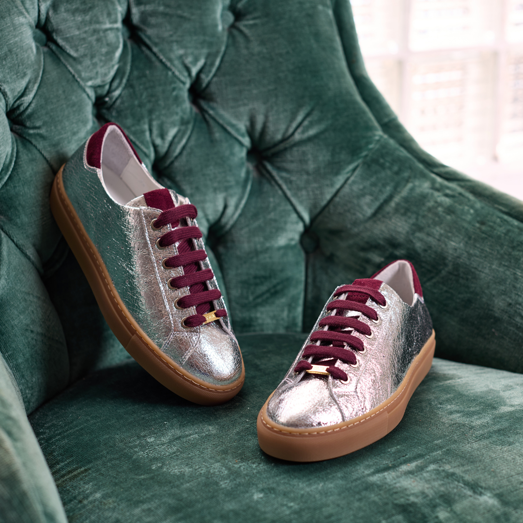 Silver star sneakers with cherry laces on a green cushioned chair