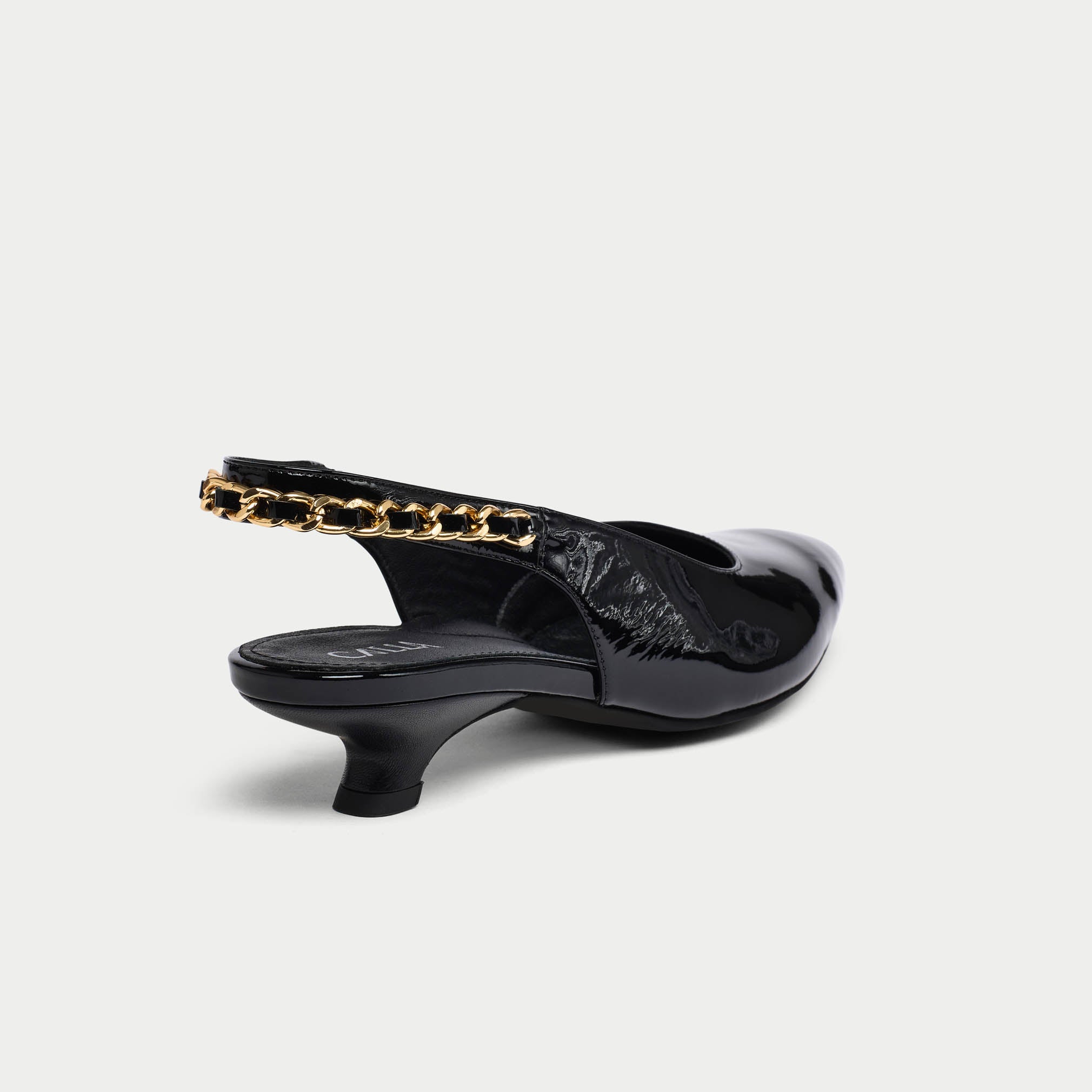 Black low-heeled Thea shoe with gold chain detail on a light gray background