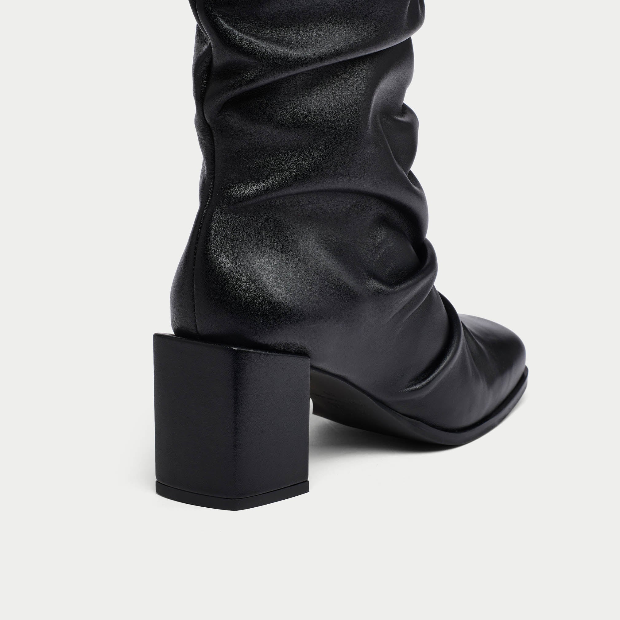 Black knee-high boot with a block heel on a white background