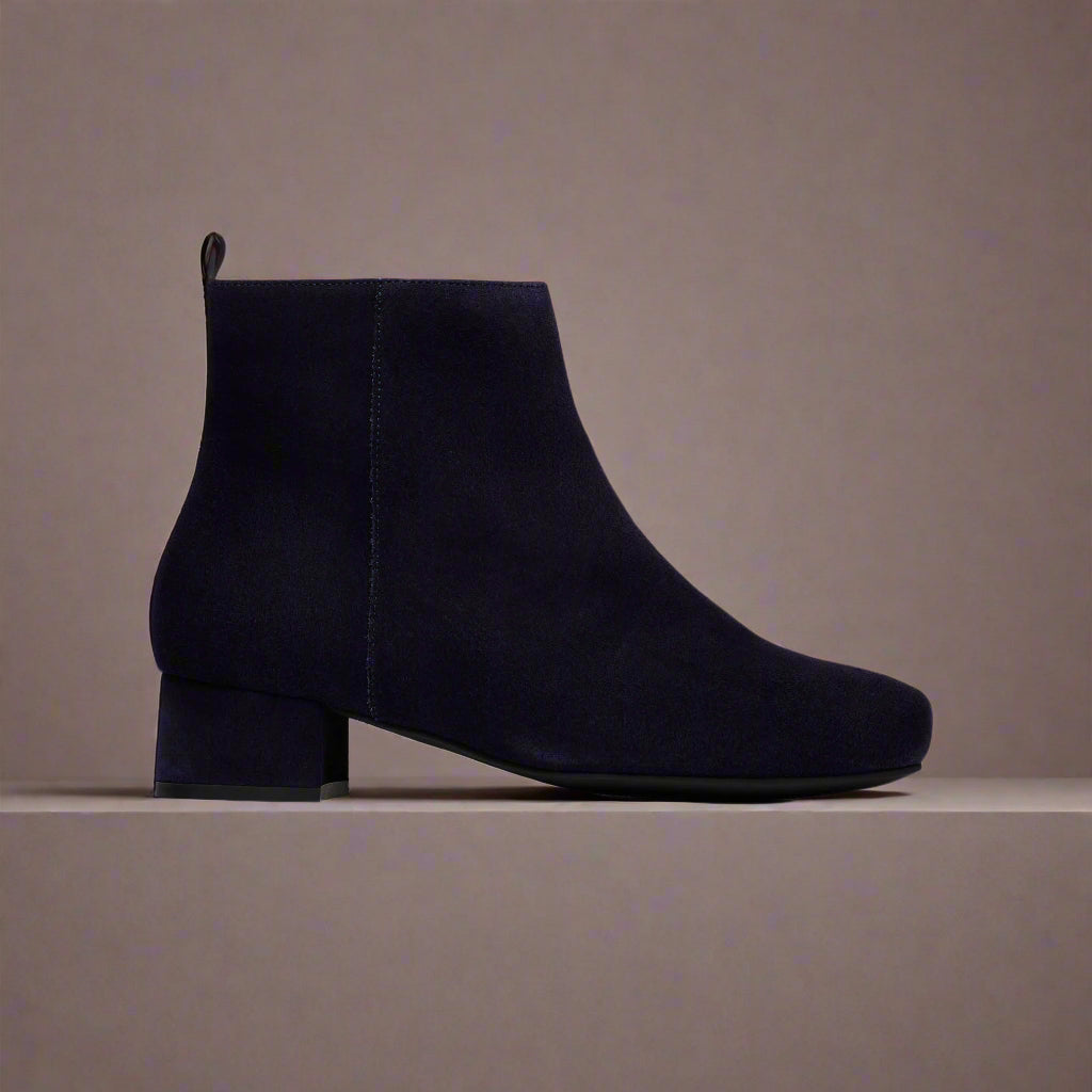 Navy blue ankle boot on a light gray background