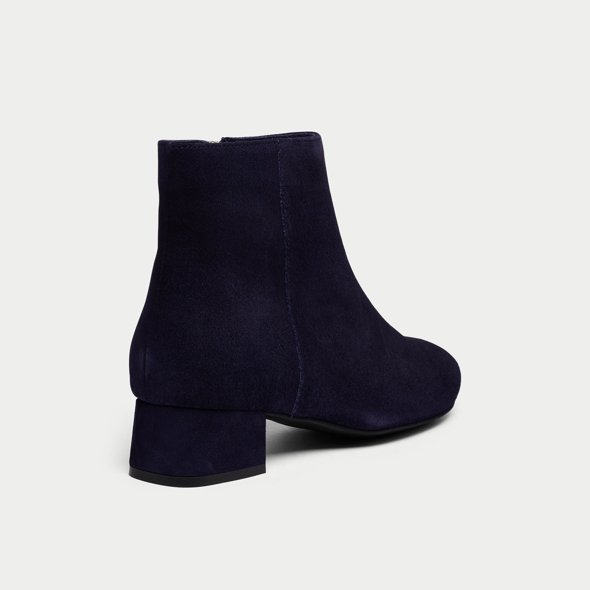 Navy blue ankle boots on a light gray background