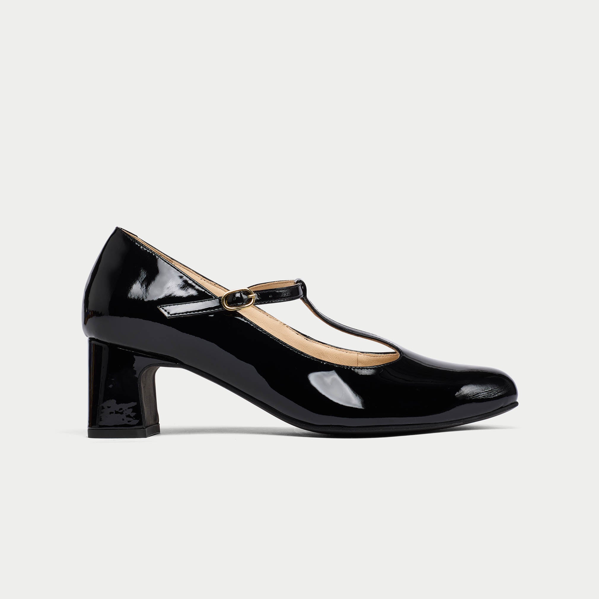 Black patent leather shoe with a strap on a light gray background