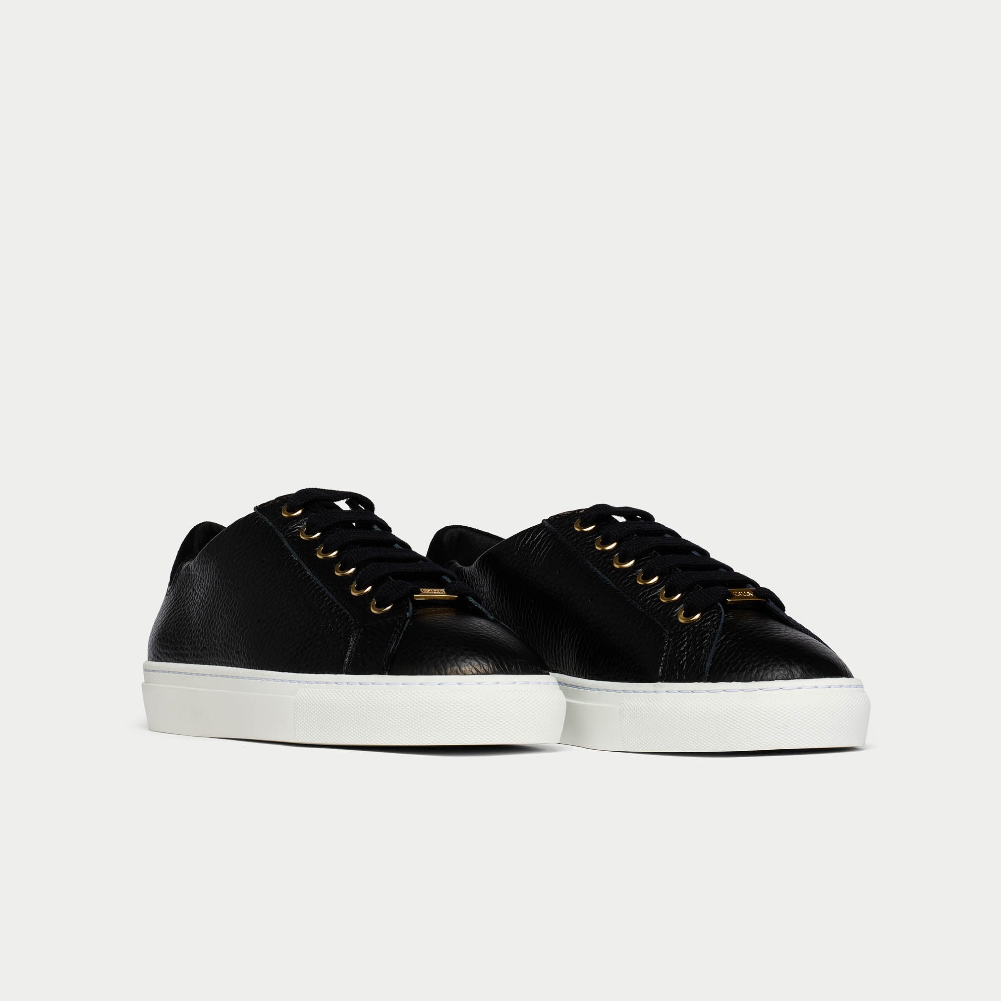 Pair of black sneakers with white soles on a light gray background