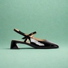 Black patent leather shoe with a strap on a green background