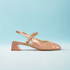 Pink patent leather shoe with a strap on a light blue background