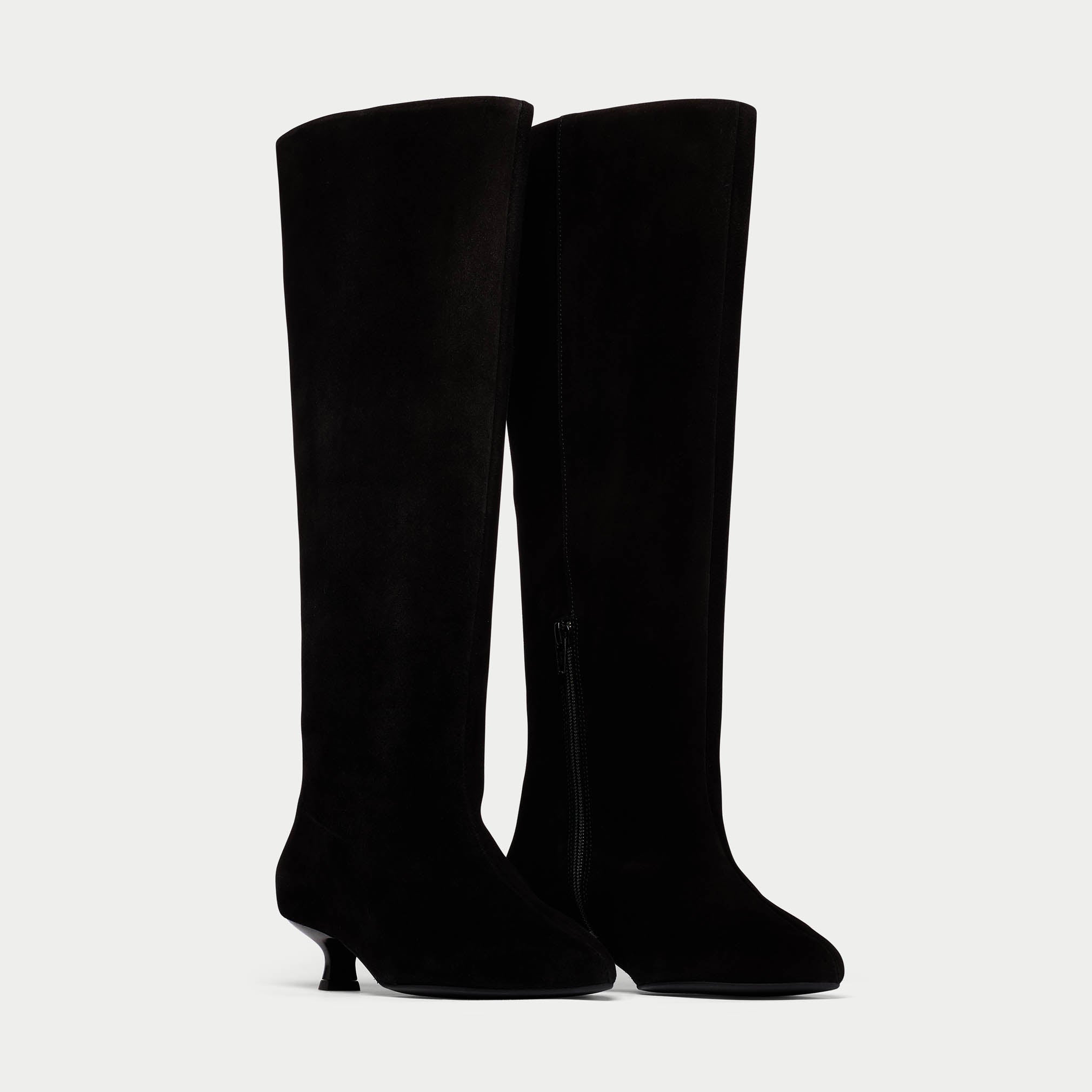 Black knee-high boots on a light gray background