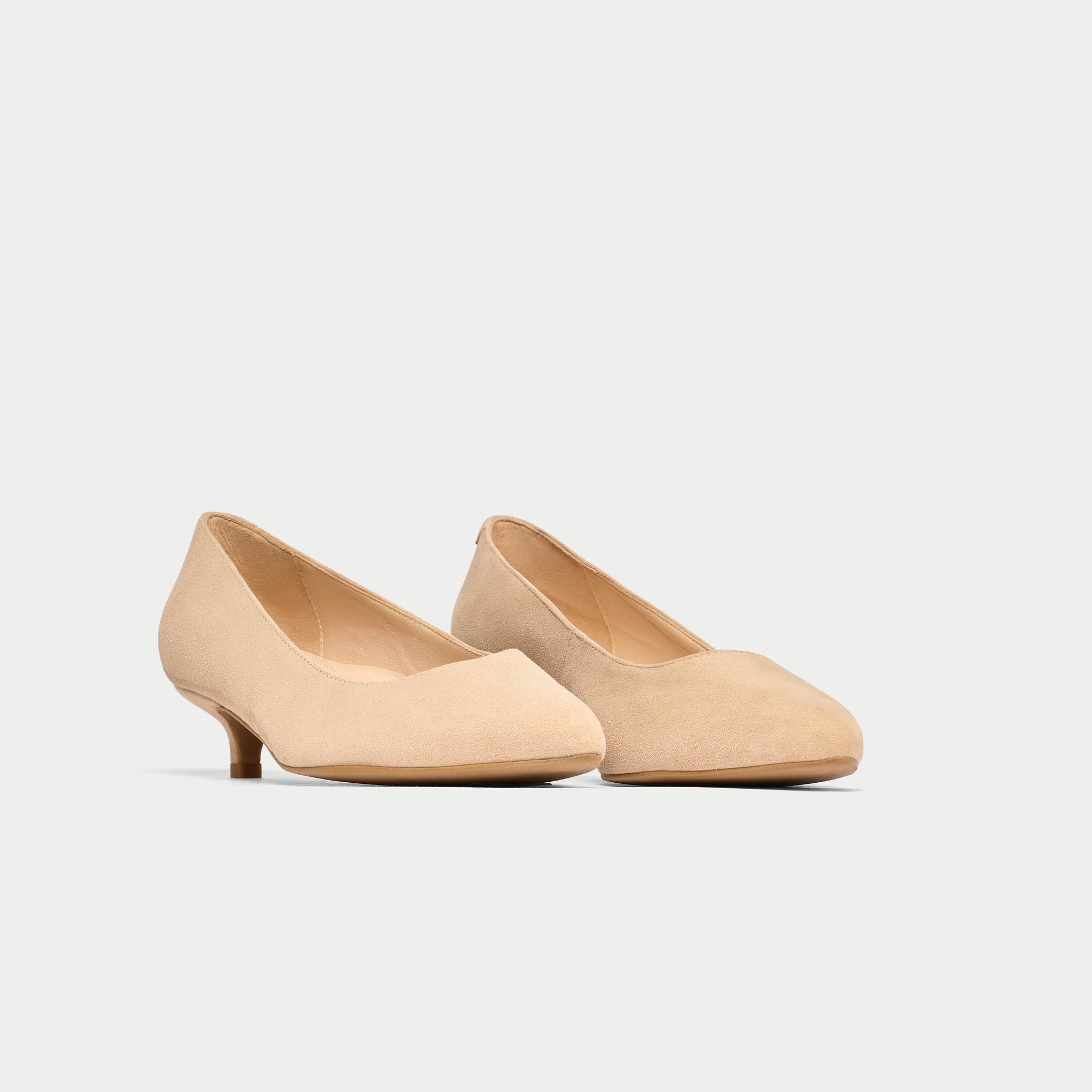 Pair of beige low heels on a light gray background