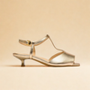 Gold sandal with a clear strap on a beige background
