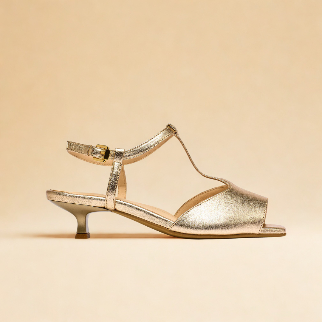 Gold sandal with a clear strap on a beige background
