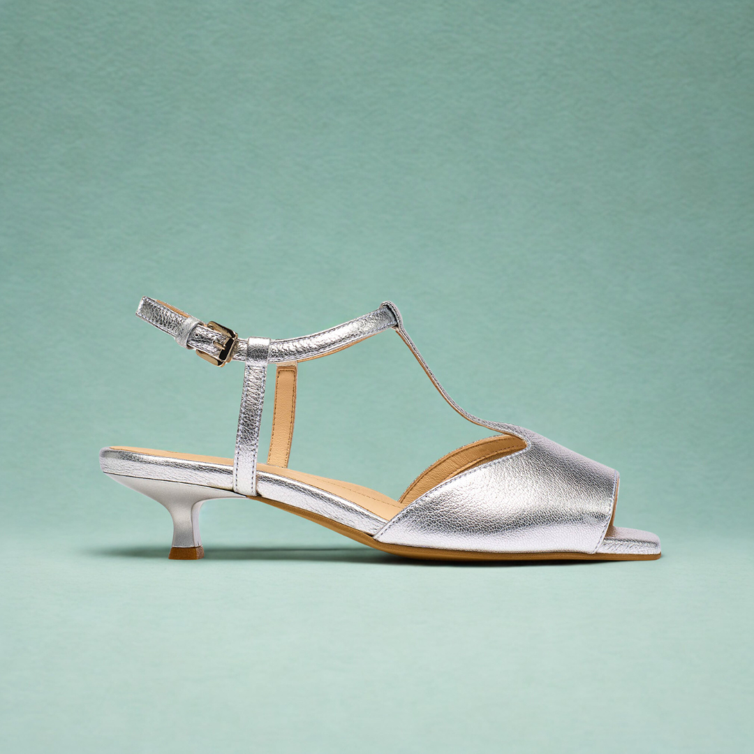 Silver sandal with open toe and kitten heel on a light green background