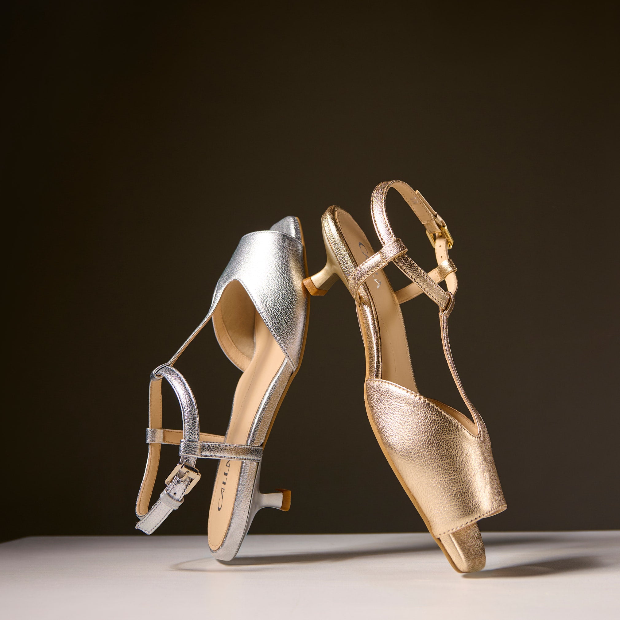 Pair of gold and silver high-heeled shoes on a dark background