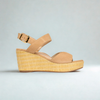 Tan wedge sandal with woven sole on a light gray background