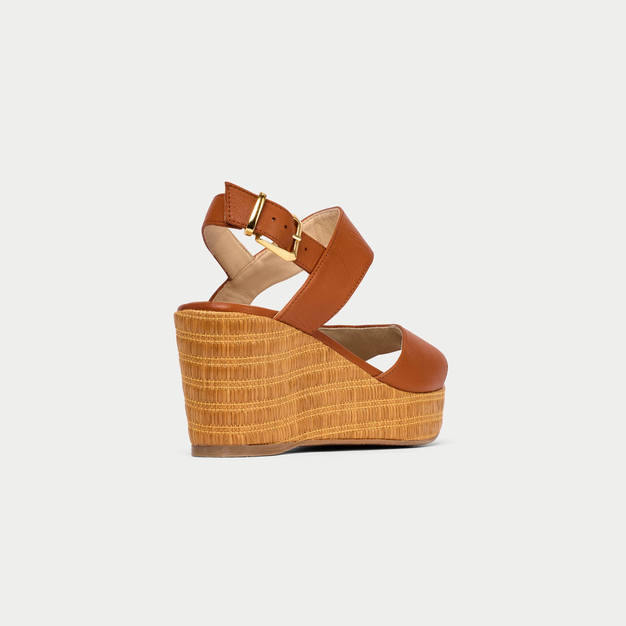 Brown wedge sandal with a strap on a light gray background