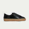Black slip-on sneaker with brown sole on a light gray background