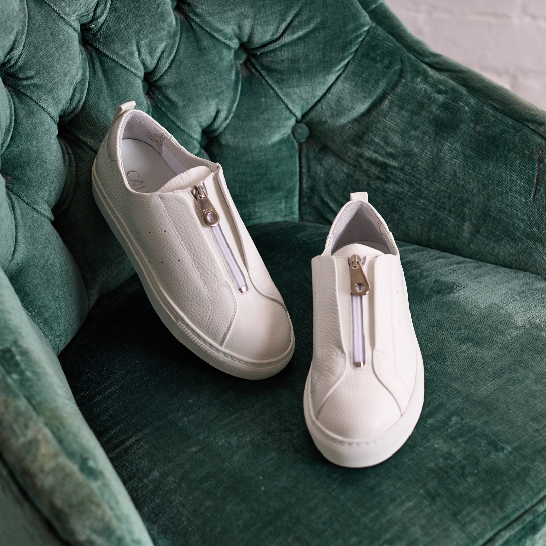 estella white trainers on green chair