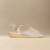 Silver sandal with a woven sole on a beige background
