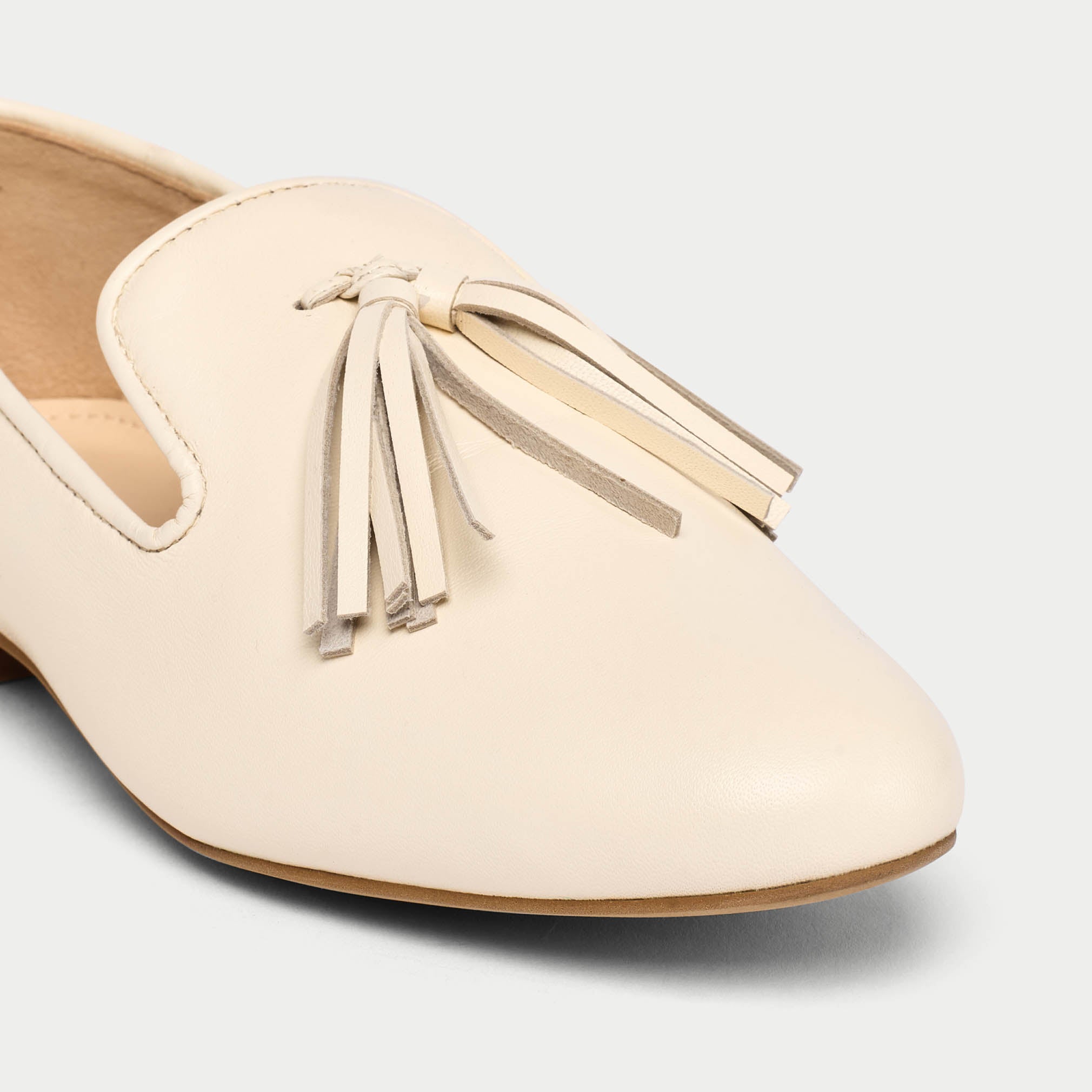 Beige loafer with tassel detail on a light gray background
