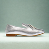 Silver loafer with tassels on teal background