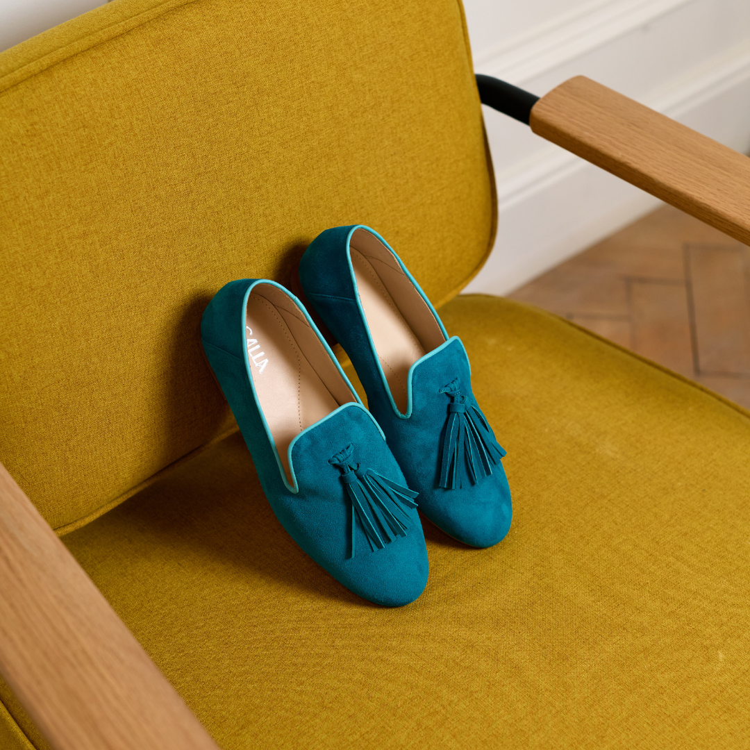 Blue suede loafers with tassels on a yellow chair