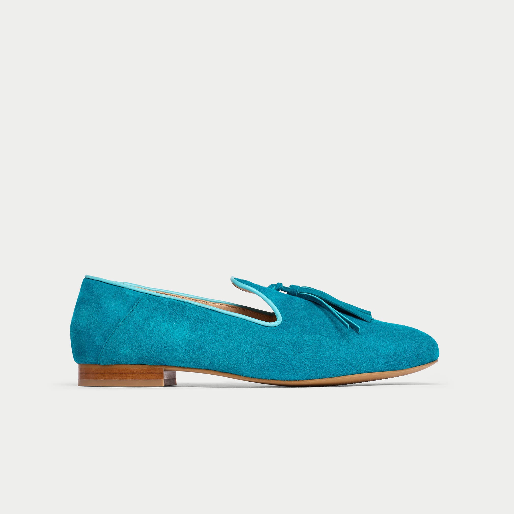 Blue suede loafer shoe on a light gray background