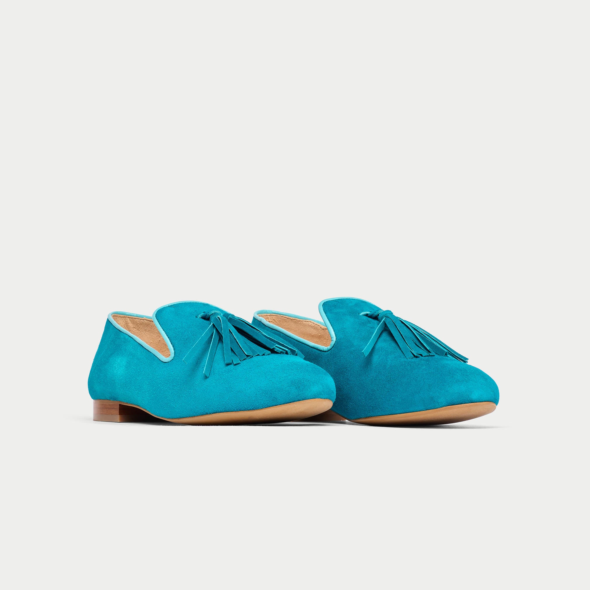Pair of turquoise loafers on a light gray background
