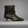Black leather ankle boot with a pointed toe on a light gray background