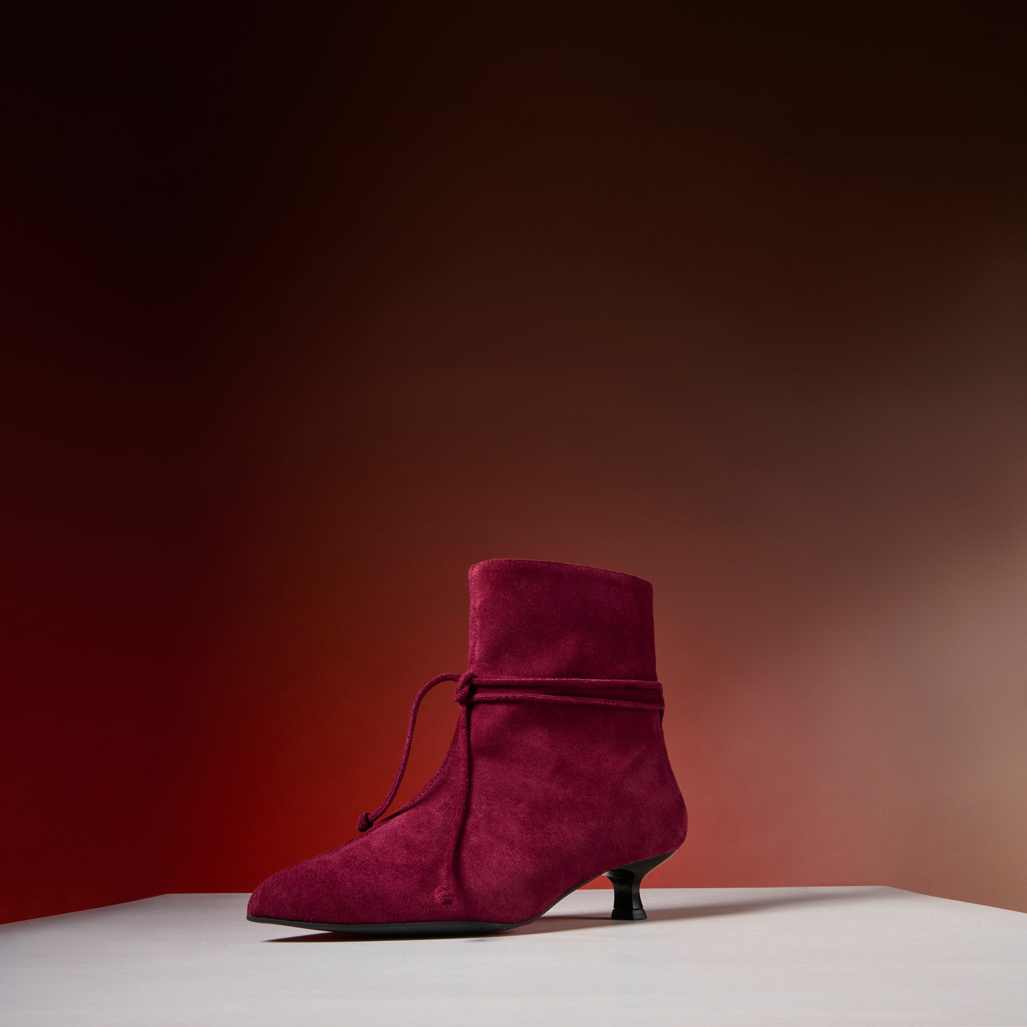 Maroon suede shoe on a gradient background