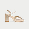 Gold high-heeled sandal on a light gray background