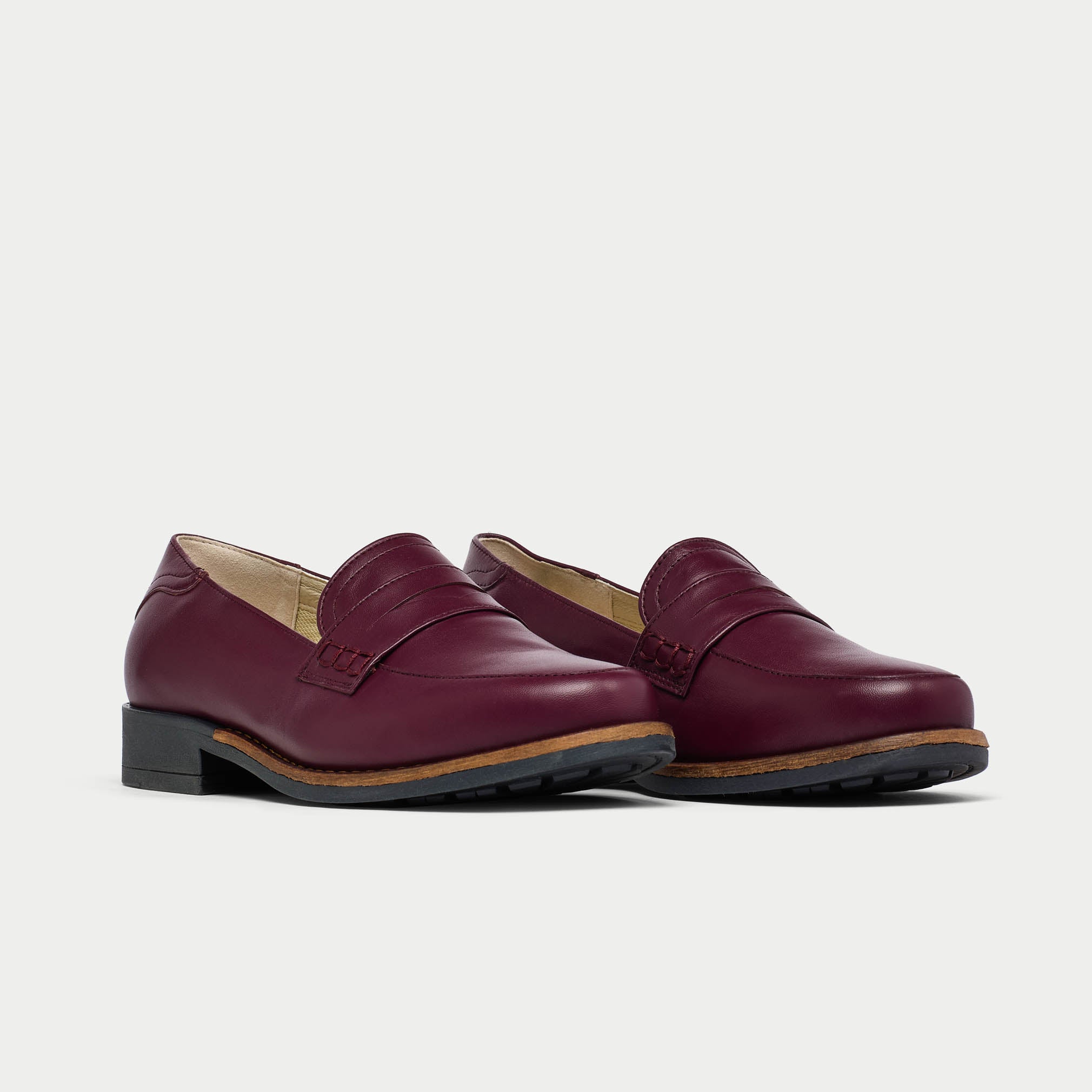 Pair of cherry Nadia loafers on a light gray background