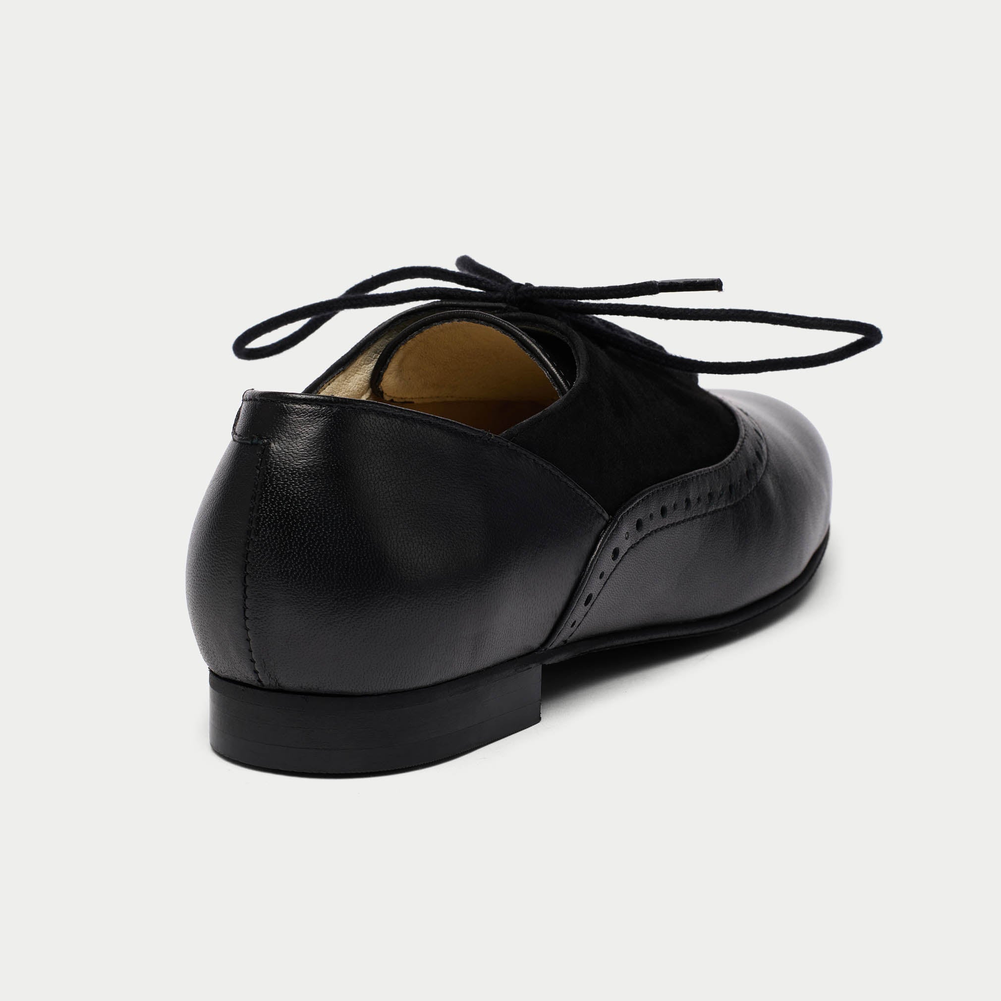 Black leather shoe with laces on a light gray background