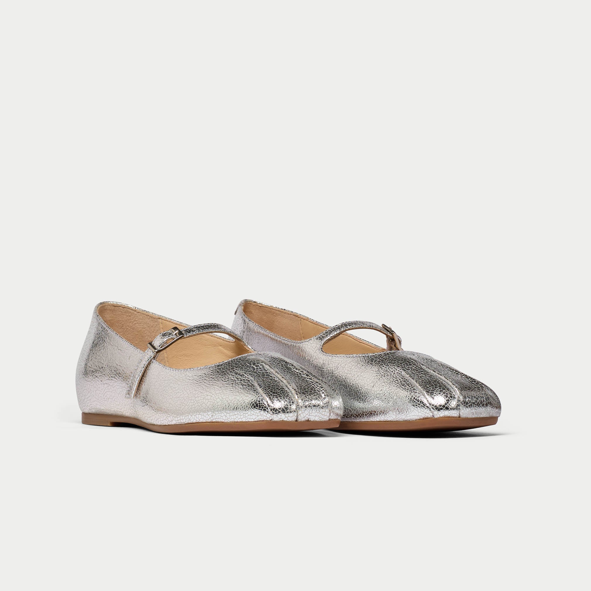 Pair of silver metallic flats on a white background
