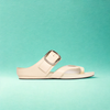 Beige sandal with a clear strap on a teal background