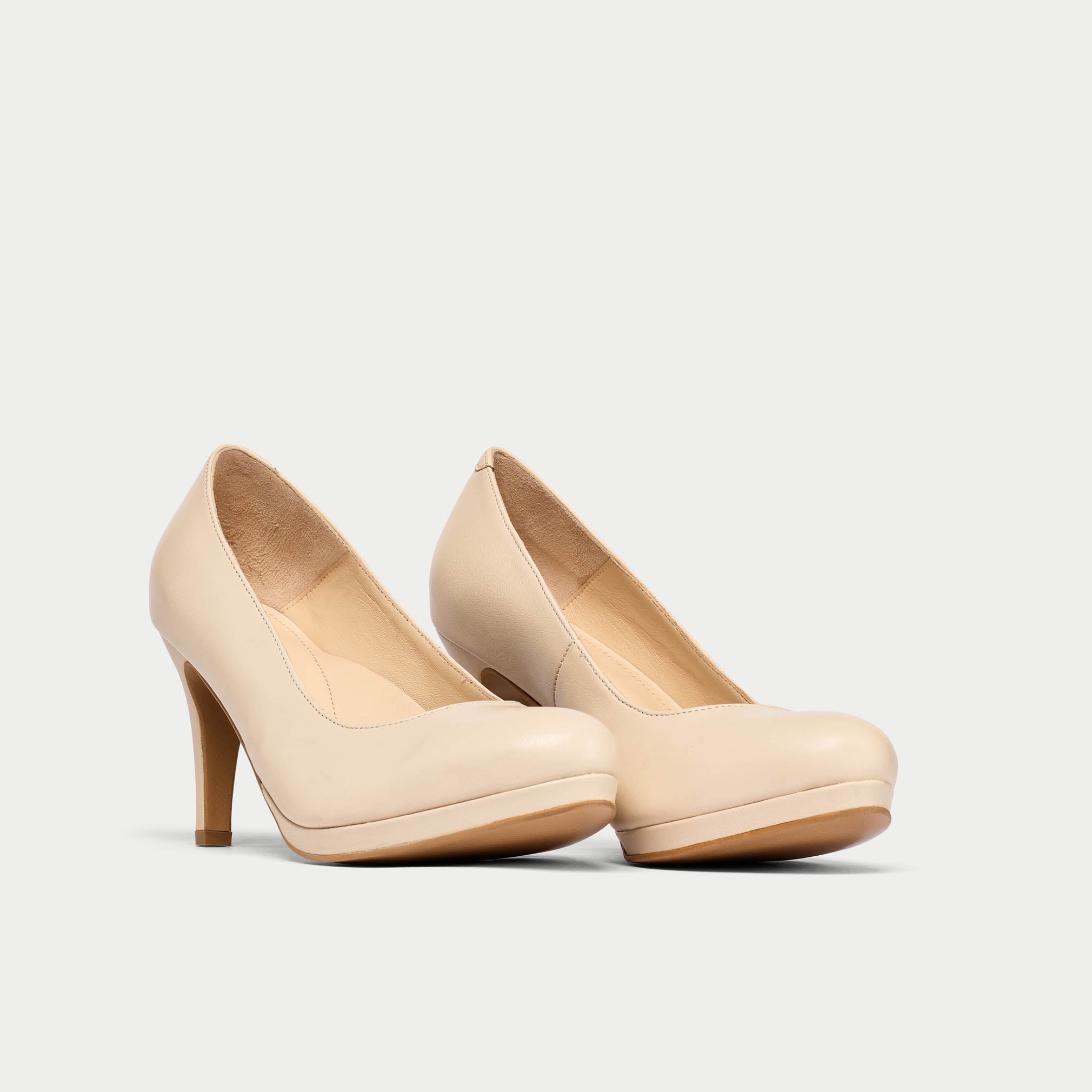 Pair of beige high-heeled shoes on a light gray background