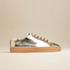 Gold metallic sneaker with a beige sole on a beige background