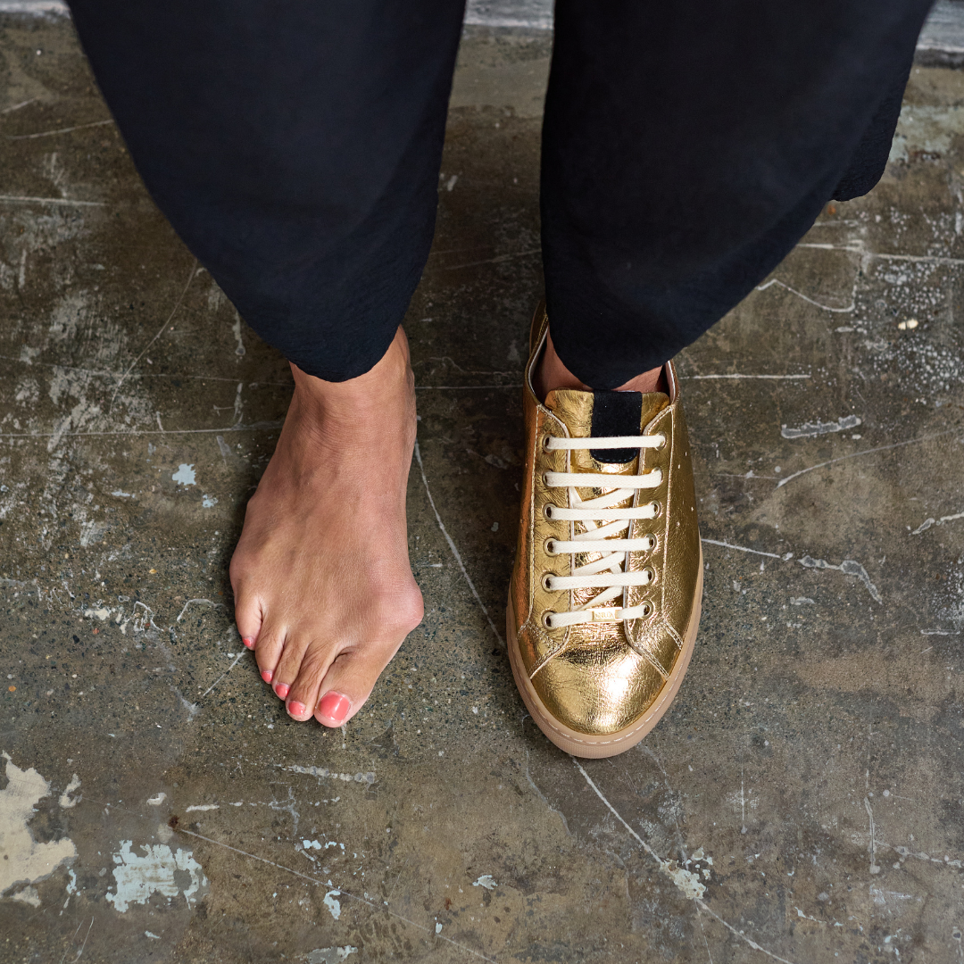 Gold sneakers worn on a concrete floor