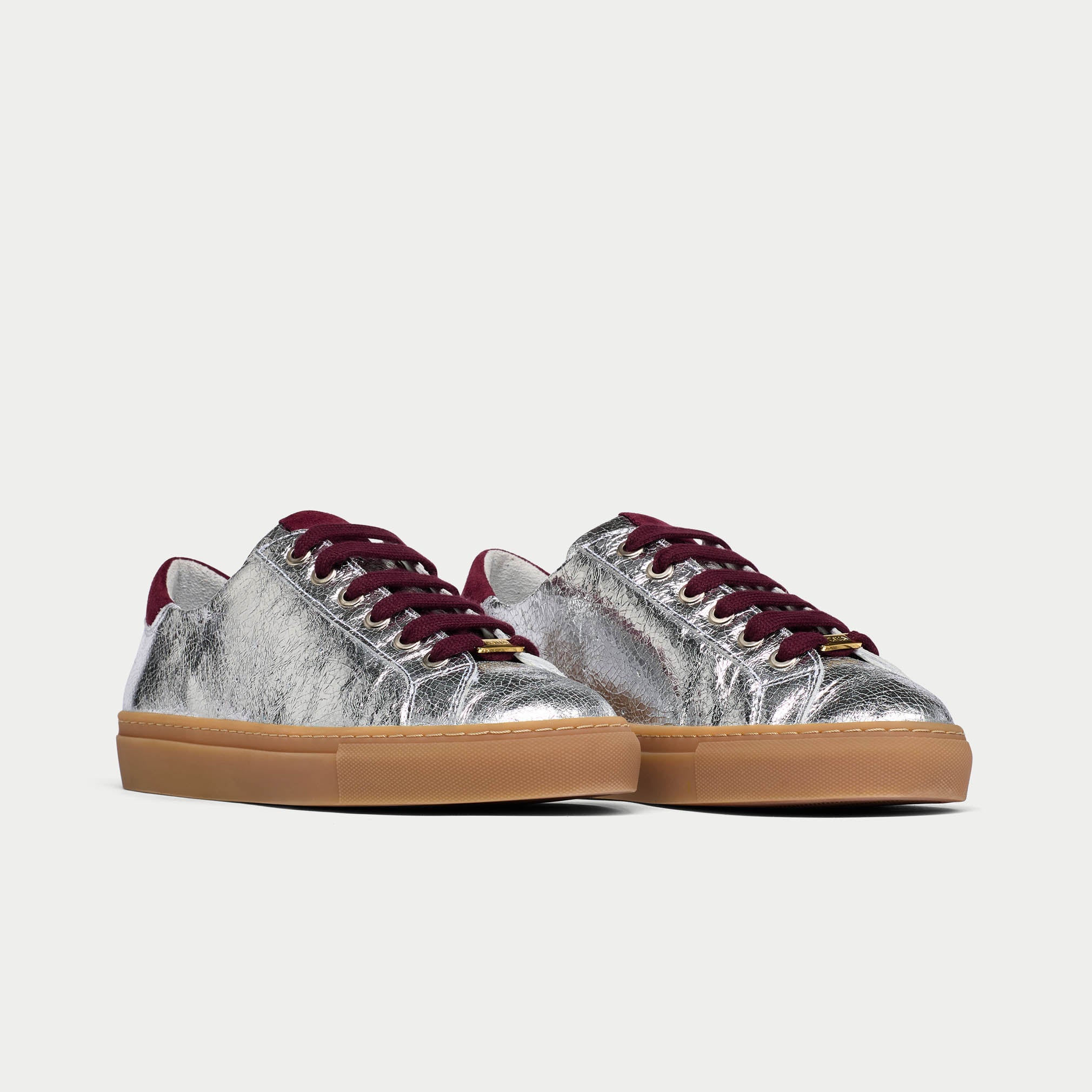 Silver star sneakers with burgundy laces and soles on a light gray background