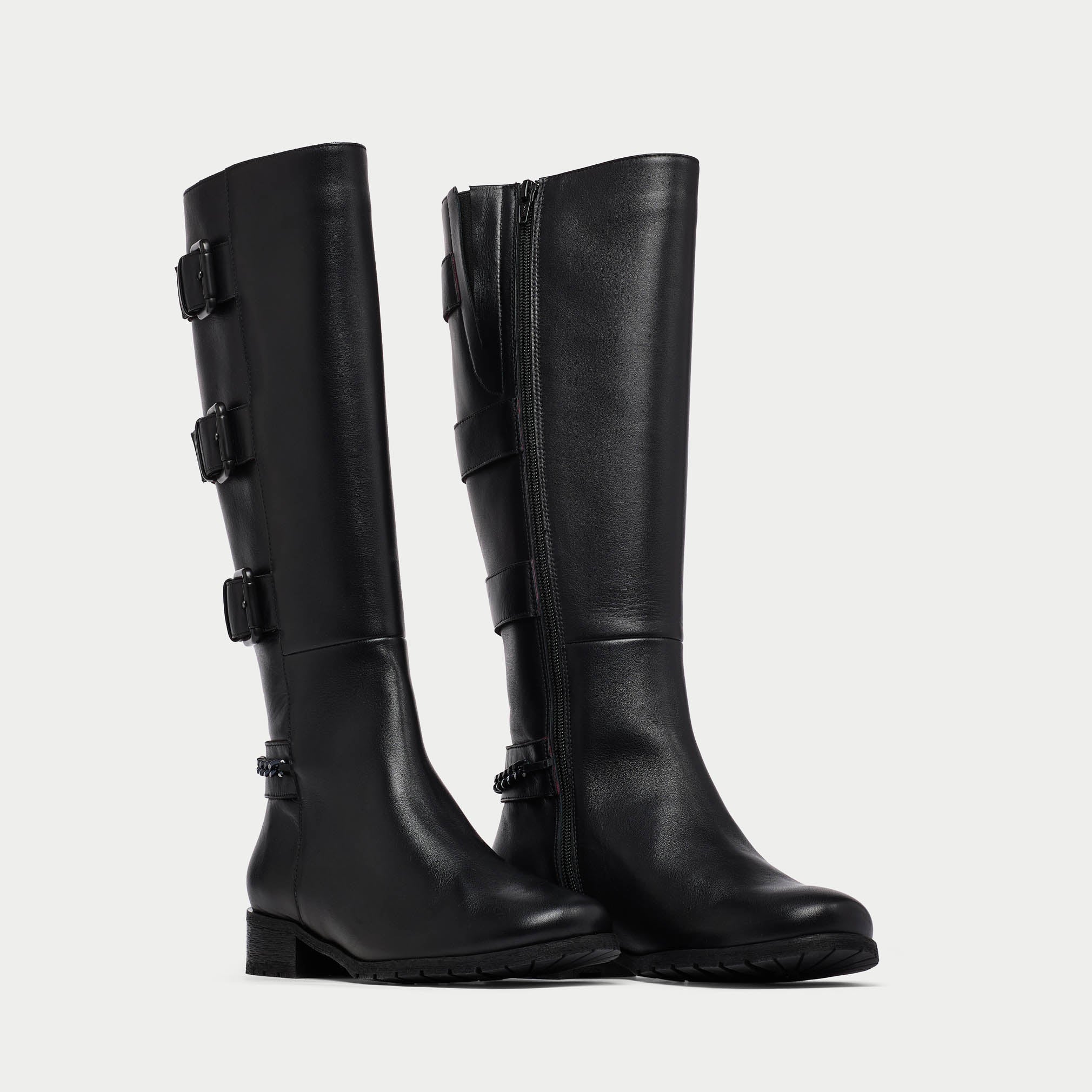 Pair of black knee-high boots with buckles on a light gray background