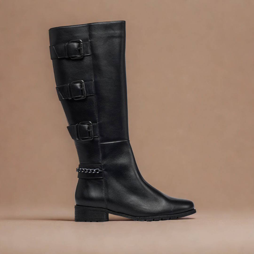 Black knee-high boot with multiple buckles on a beige background