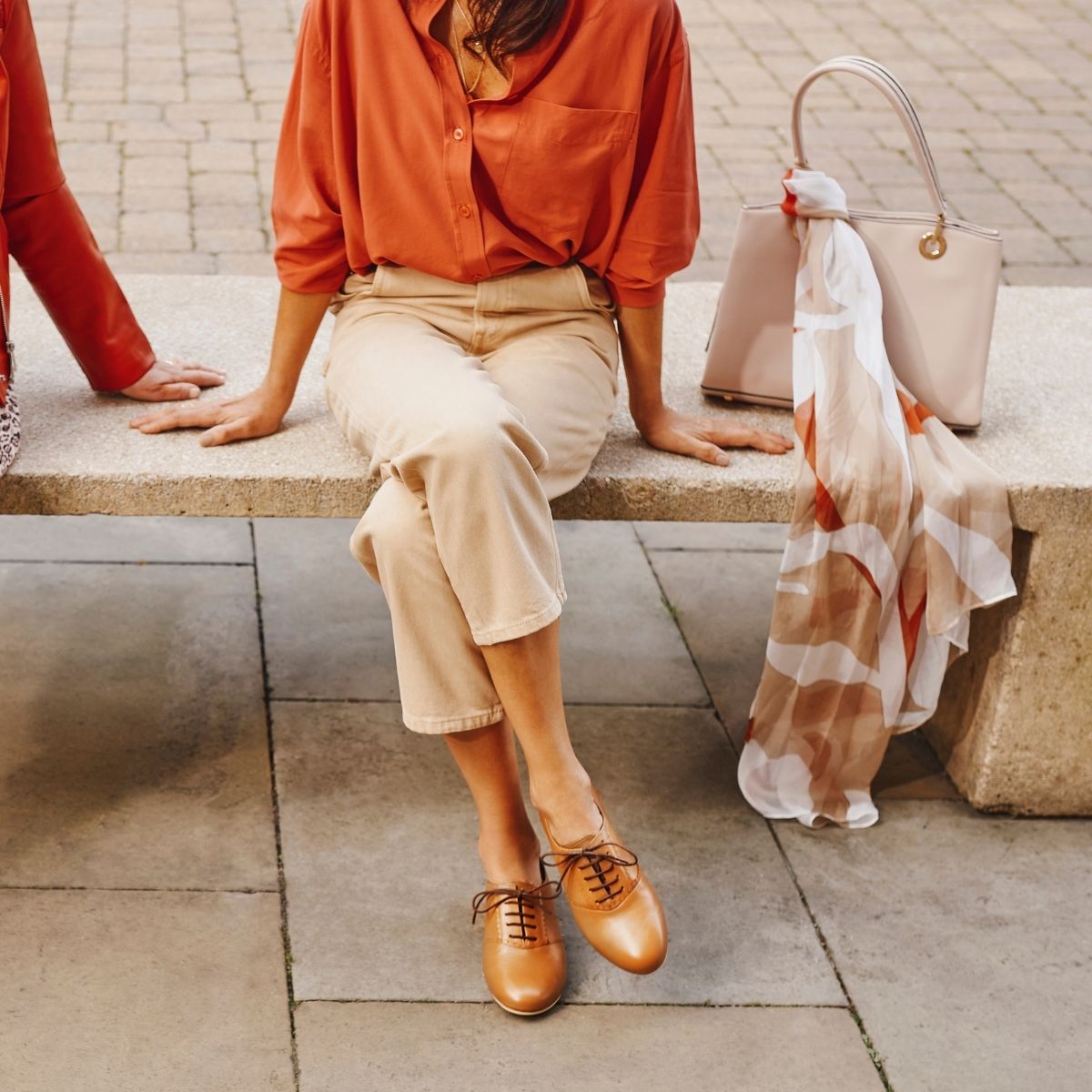woman sitting on a bench in red shirt and brogue shoes