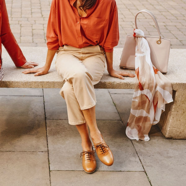 woman sitting on a bench in red shirt and brogue shoes