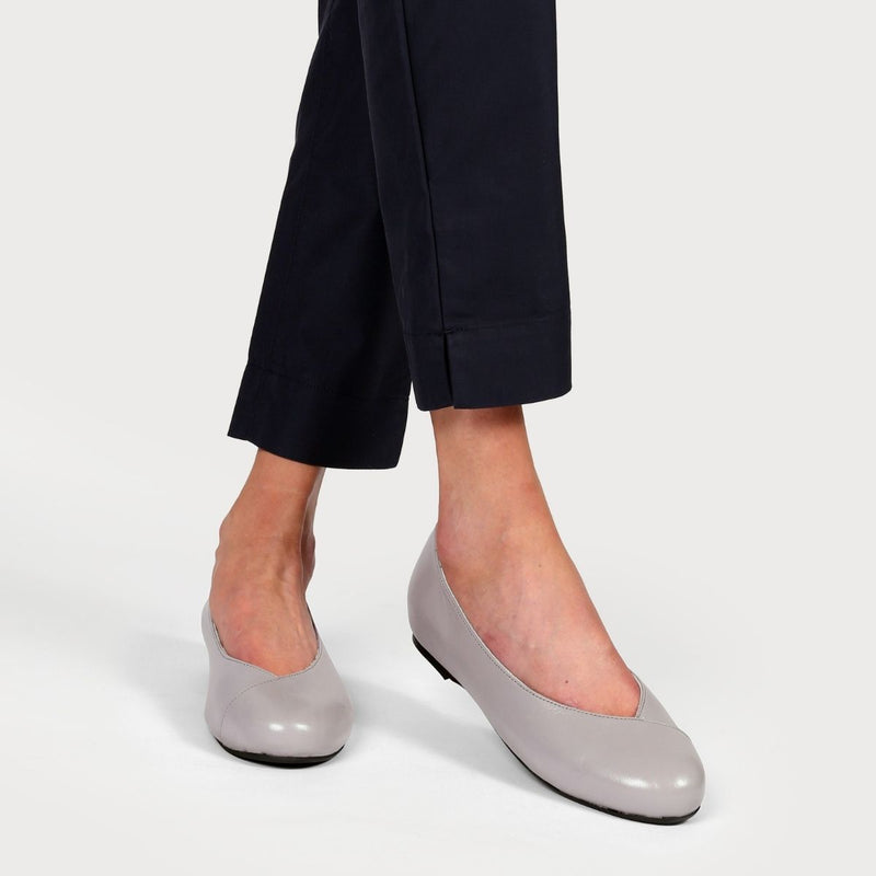 grey leather flats on crossed legs in navy trousers